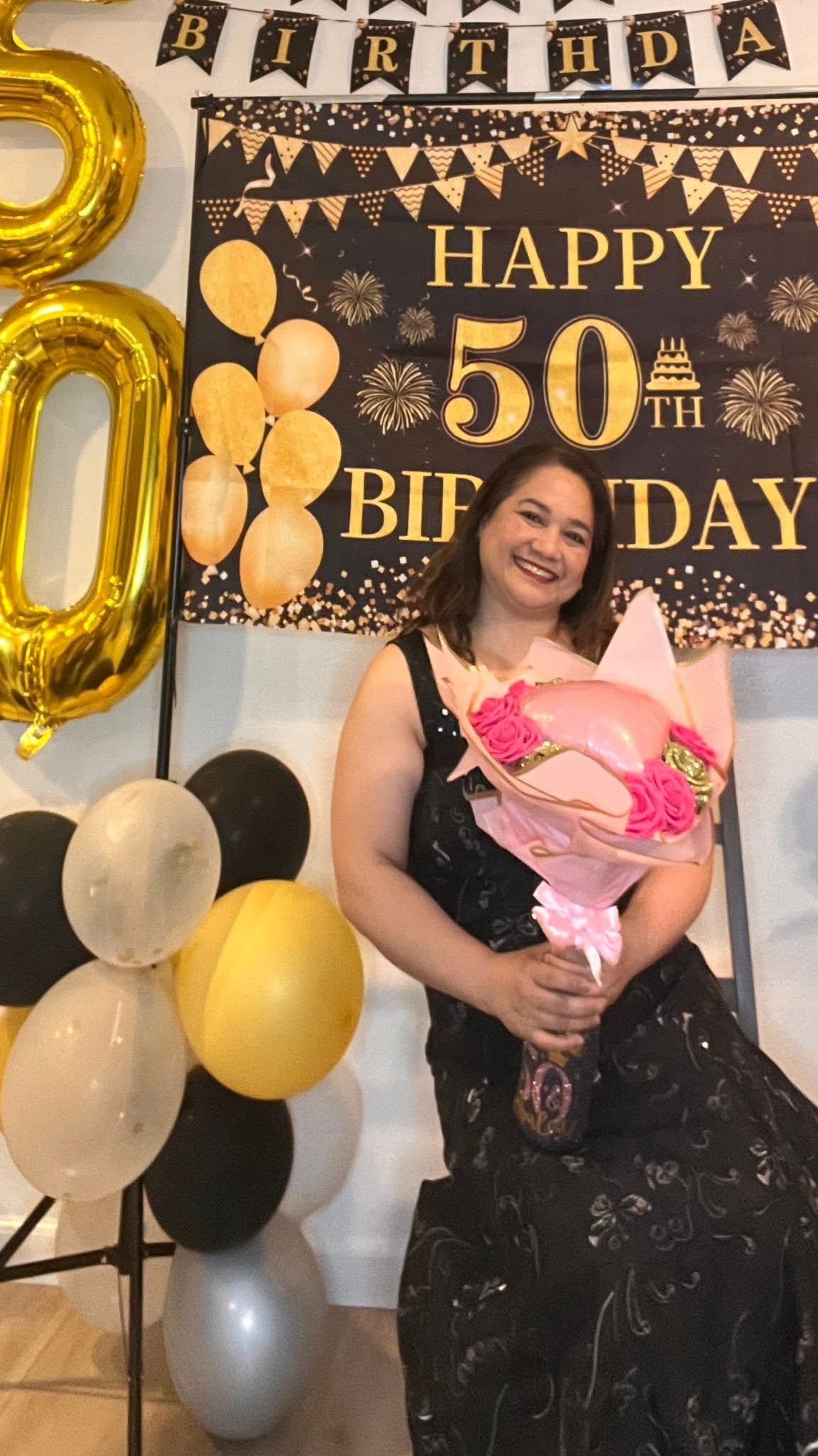 Customer holding a custom glitter bottle flower bouquet with a pink heart balloon
